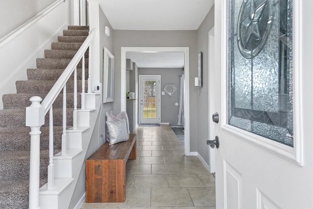 entrance foyer featuring stairs, baseboards, and light tile patterned flooring