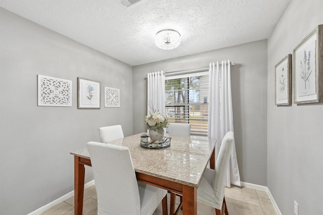 dining area with light tile patterned floors, baseboards, and a textured ceiling