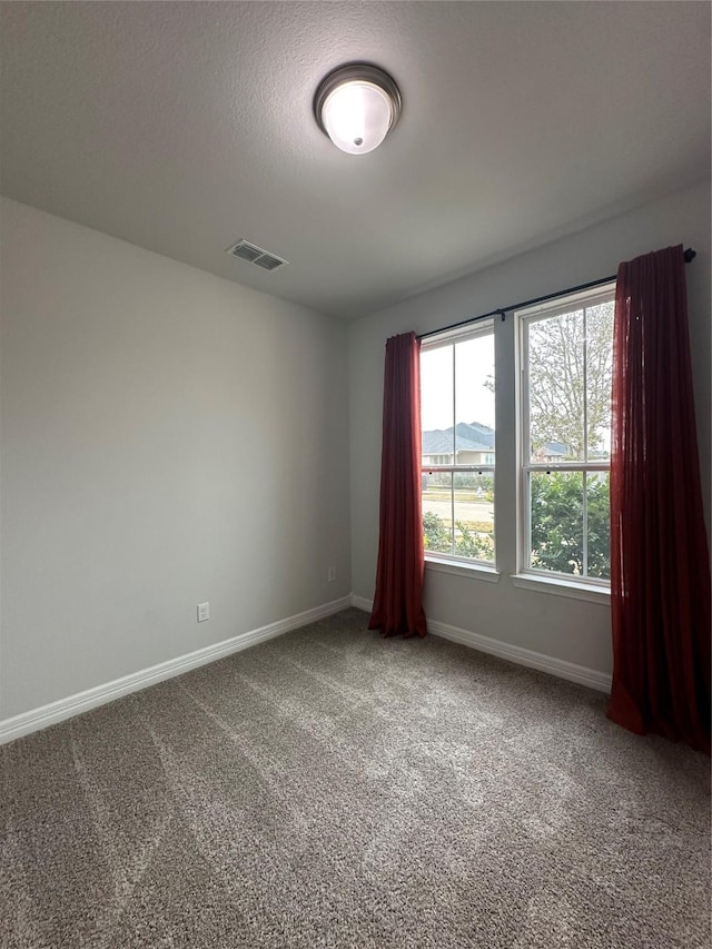 carpeted spare room with a textured ceiling