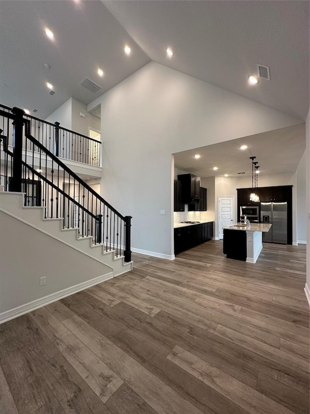 unfurnished living room with dark hardwood / wood-style flooring, sink, and high vaulted ceiling