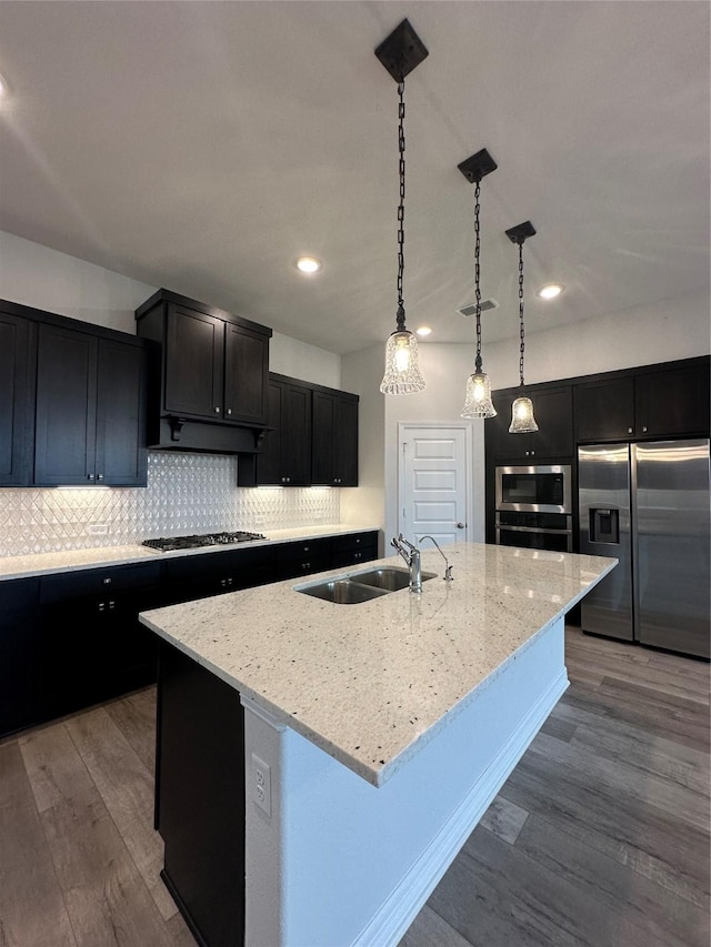 kitchen with sink, decorative light fixtures, an island with sink, hardwood / wood-style flooring, and stainless steel appliances