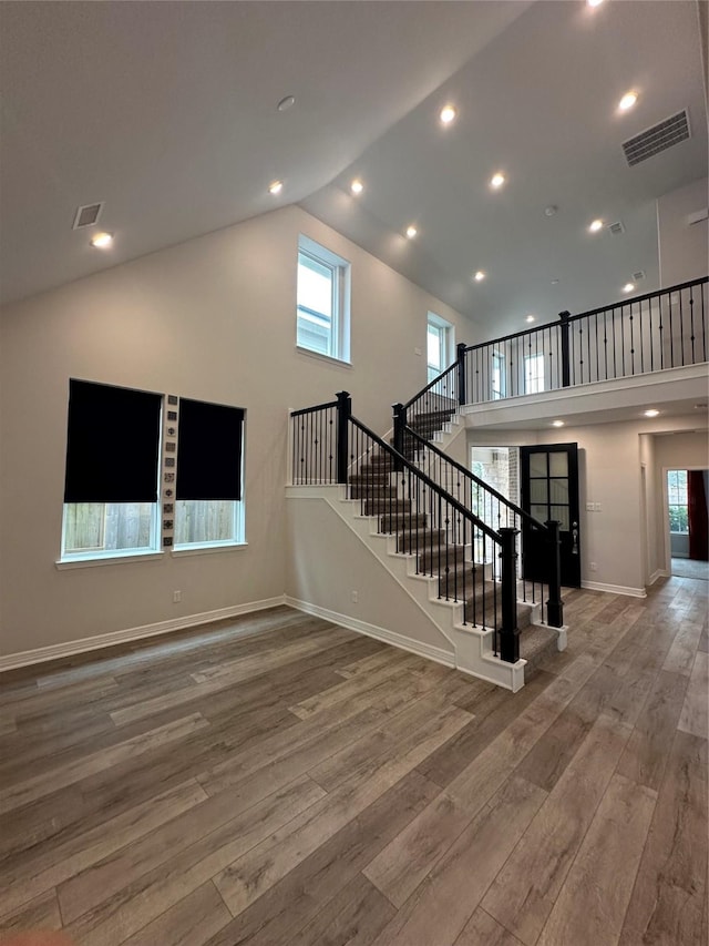 stairs with wood-type flooring and high vaulted ceiling