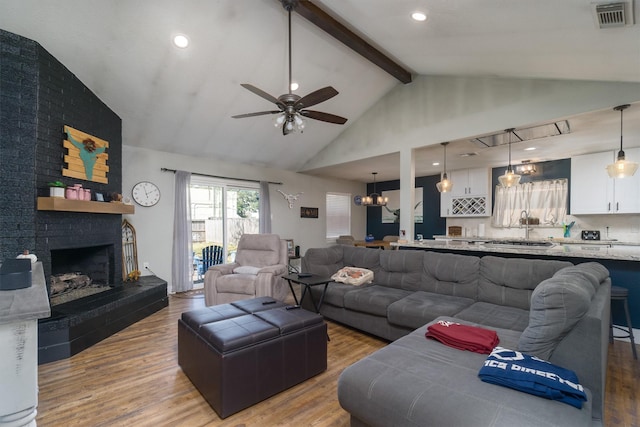 living room with ceiling fan, hardwood / wood-style floors, a fireplace, and beam ceiling