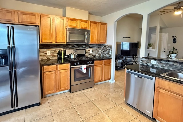 kitchen featuring light tile patterned floors, sink, ceiling fan, backsplash, and stainless steel appliances