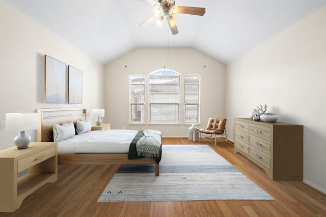 bedroom with ceiling fan, lofted ceiling, and light wood-type flooring