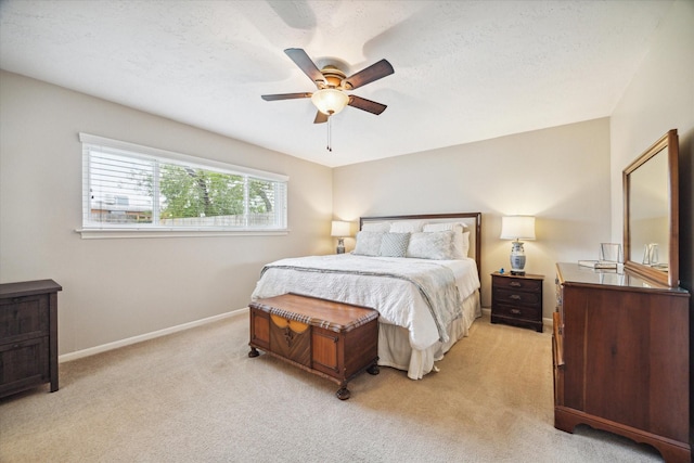 bedroom with light carpet, ceiling fan, and a textured ceiling