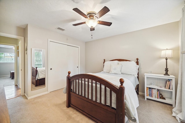 carpeted bedroom with ceiling fan and a closet