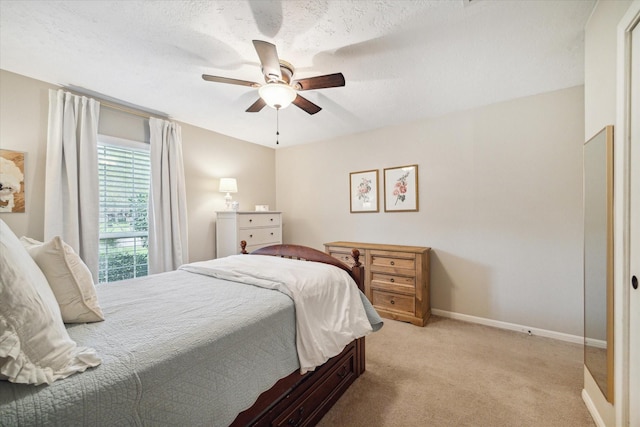 bedroom with ceiling fan, light colored carpet, and a textured ceiling