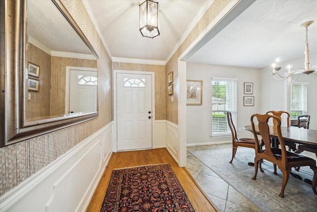 entrance foyer featuring an inviting chandelier, ornamental molding, and light hardwood / wood-style flooring