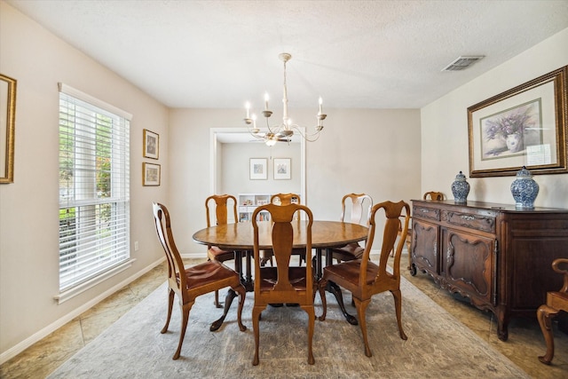 tiled dining space featuring a chandelier and a textured ceiling