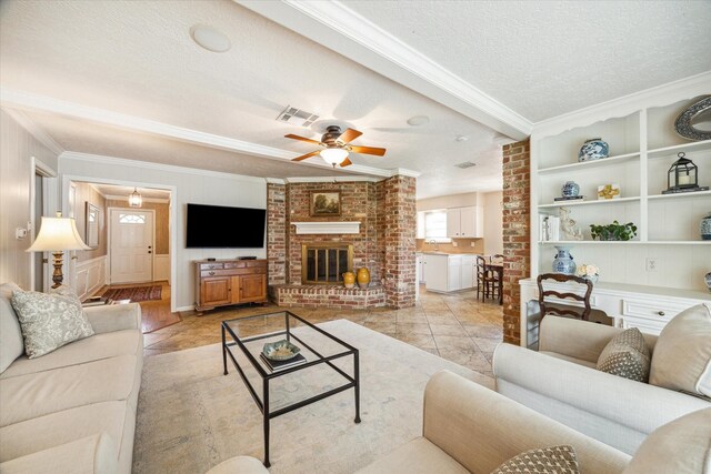 living room with crown molding, a brick fireplace, a textured ceiling, light tile patterned floors, and ceiling fan