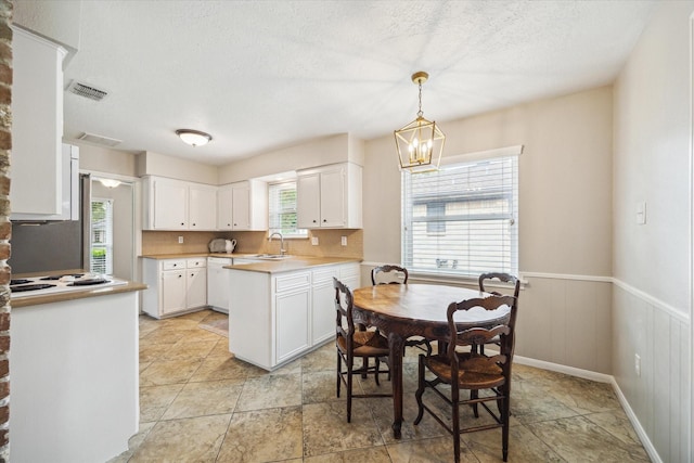 kitchen featuring tasteful backsplash, hanging light fixtures, a notable chandelier, white appliances, and white cabinets