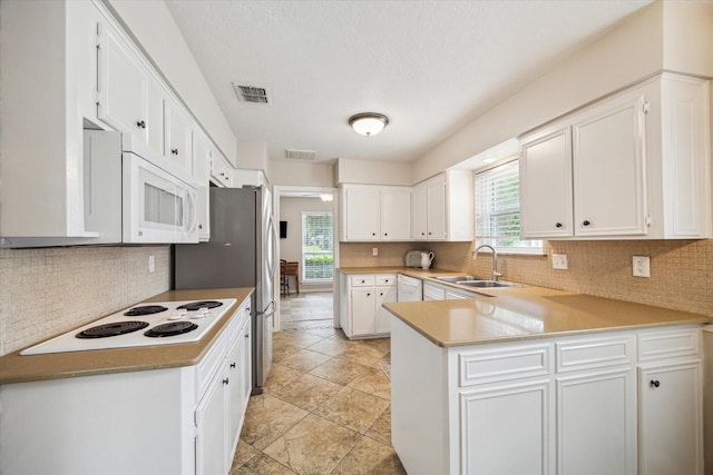 kitchen featuring sink, white appliances, a wealth of natural light, white cabinets, and kitchen peninsula