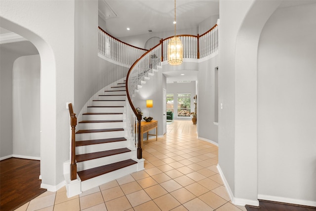 entryway featuring a high ceiling, light tile patterned floors, and an inviting chandelier