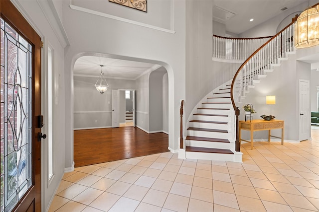 foyer entrance featuring a high ceiling, plenty of natural light, light tile patterned floors, and an inviting chandelier