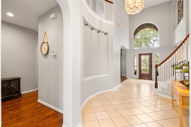 tiled foyer featuring an inviting chandelier and a high ceiling