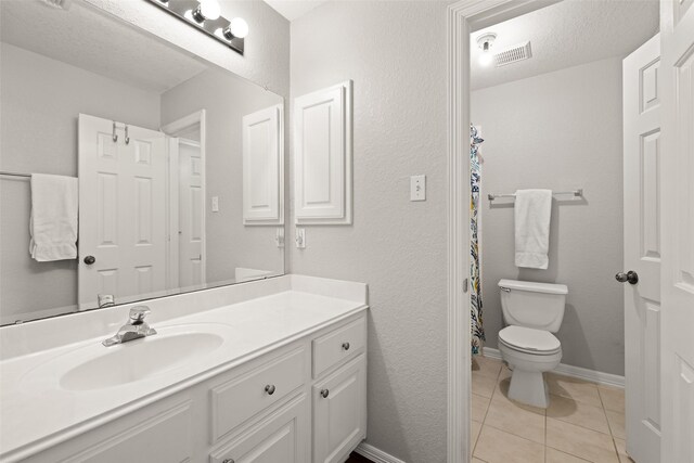 bathroom featuring vanity, tile patterned floors, toilet, and a textured ceiling