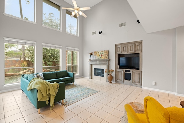 tiled living room with ceiling fan and a fireplace