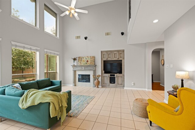 tiled living room with a tile fireplace and ceiling fan