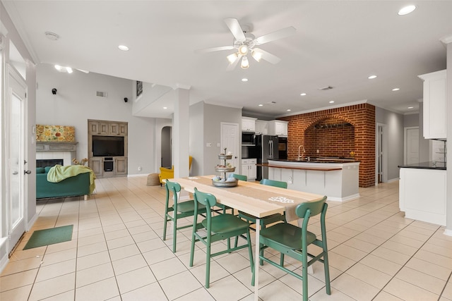 dining room with ceiling fan, ornamental molding, a fireplace, and light tile patterned floors