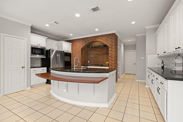 kitchen featuring light tile patterned floors, sink, tasteful backsplash, white cabinets, and built in microwave