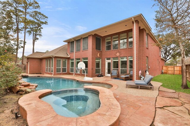 back of property featuring a swimming pool with hot tub and a patio