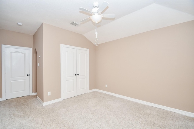 unfurnished bedroom with vaulted ceiling, light colored carpet, a closet, and ceiling fan