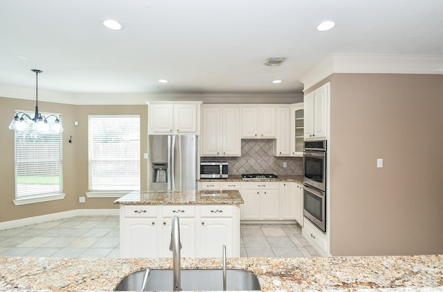 kitchen with sink, white cabinetry, hanging light fixtures, stainless steel appliances, and light stone countertops