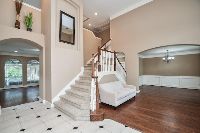 stairs featuring crown molding, a towering ceiling, and hardwood / wood-style flooring