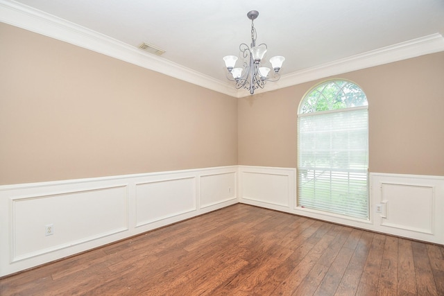 empty room with a notable chandelier, crown molding, and dark wood-type flooring