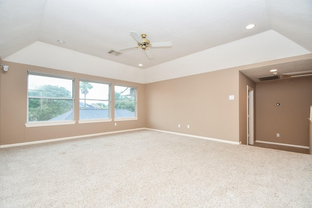 carpeted spare room featuring a raised ceiling, vaulted ceiling, and ceiling fan