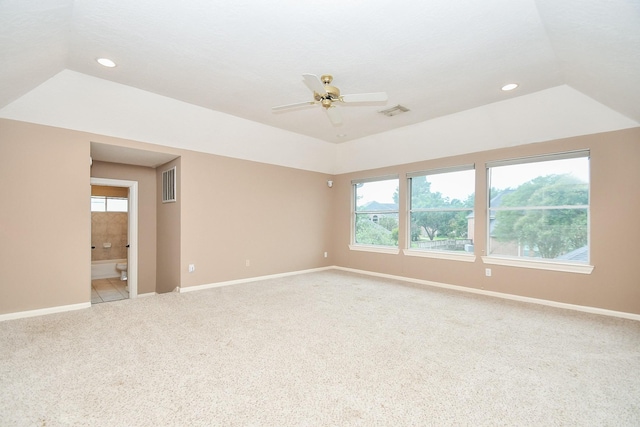 spare room featuring light carpet, a tray ceiling, vaulted ceiling, and ceiling fan