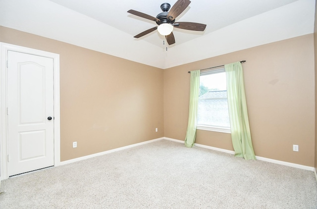 carpeted empty room featuring a tray ceiling and ceiling fan