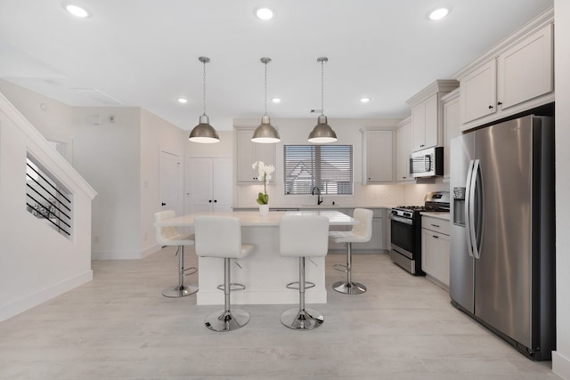 kitchen with a center island, appliances with stainless steel finishes, a breakfast bar, and decorative light fixtures