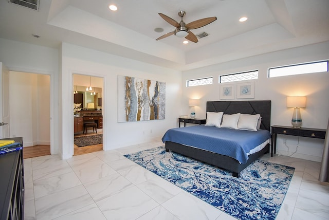 bedroom featuring ceiling fan, a raised ceiling, and connected bathroom