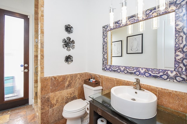 bathroom with tile walls, sink, and toilet