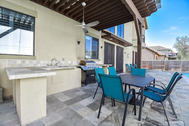 view of patio / terrace with ceiling fan, an outdoor kitchen, a grill, and a wet bar