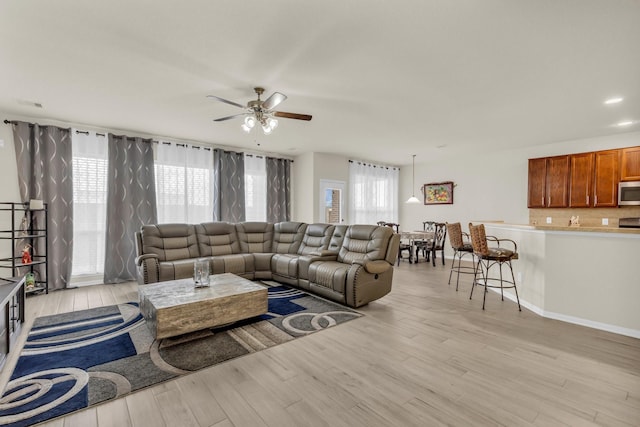 living room with a wealth of natural light, ceiling fan, and light hardwood / wood-style flooring