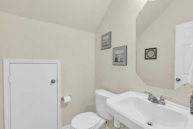 bathroom featuring toilet, sink, and vaulted ceiling