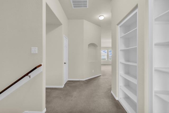 hallway featuring light carpet and built in shelves