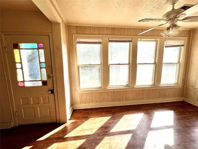 interior space featuring plenty of natural light, ceiling fan, and wood walls