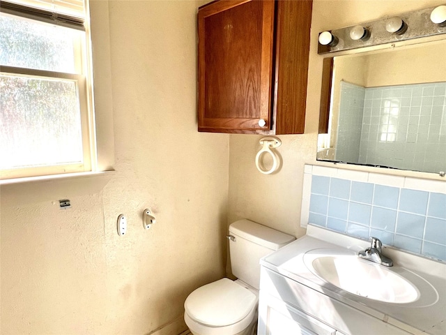 bathroom featuring vanity, toilet, decorative backsplash, and a wealth of natural light