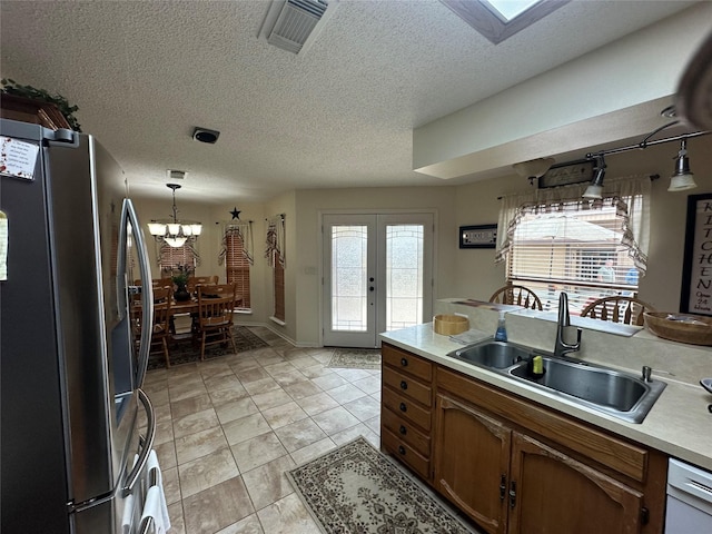 kitchen with visible vents, brown cabinets, light countertops, stainless steel refrigerator with ice dispenser, and a sink