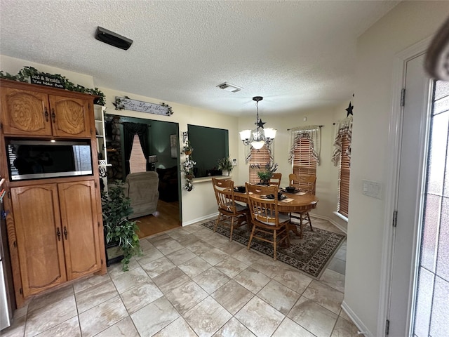 dining space with an inviting chandelier, visible vents, and a textured ceiling