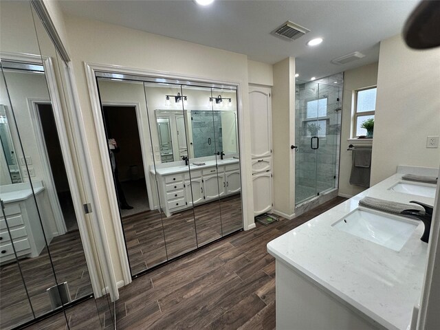 bathroom featuring wood tiled floor, vanity, visible vents, and a shower stall