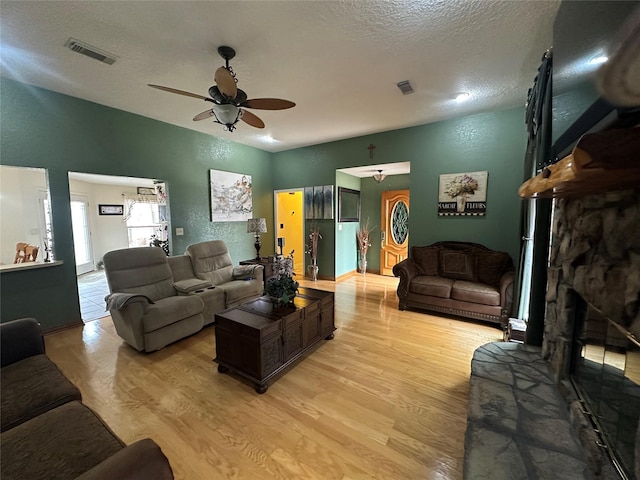 living area with visible vents, light wood-style flooring, and a textured ceiling