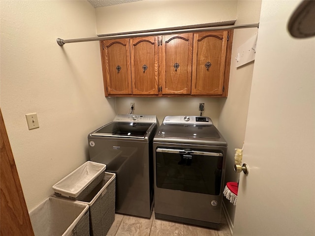 clothes washing area with cabinet space, light wood-style floors, and washer and dryer