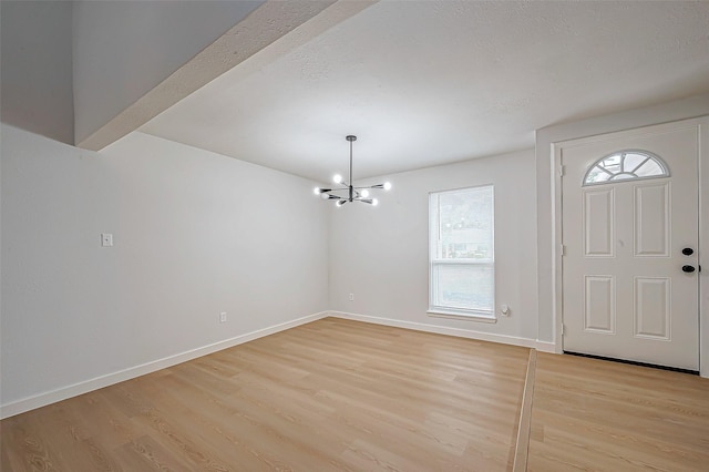 foyer entrance with light hardwood / wood-style floors and a chandelier