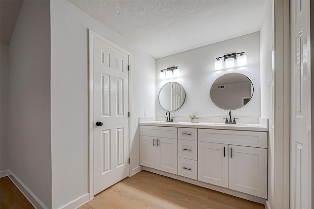 bathroom featuring hardwood / wood-style flooring, vanity, and a textured ceiling