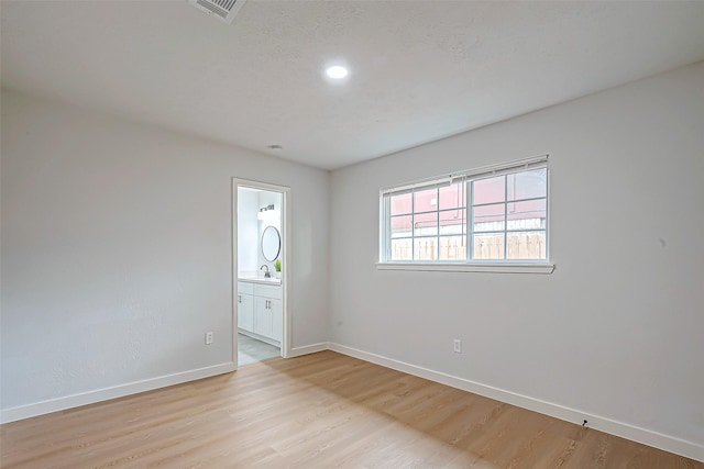 empty room featuring sink and light hardwood / wood-style flooring